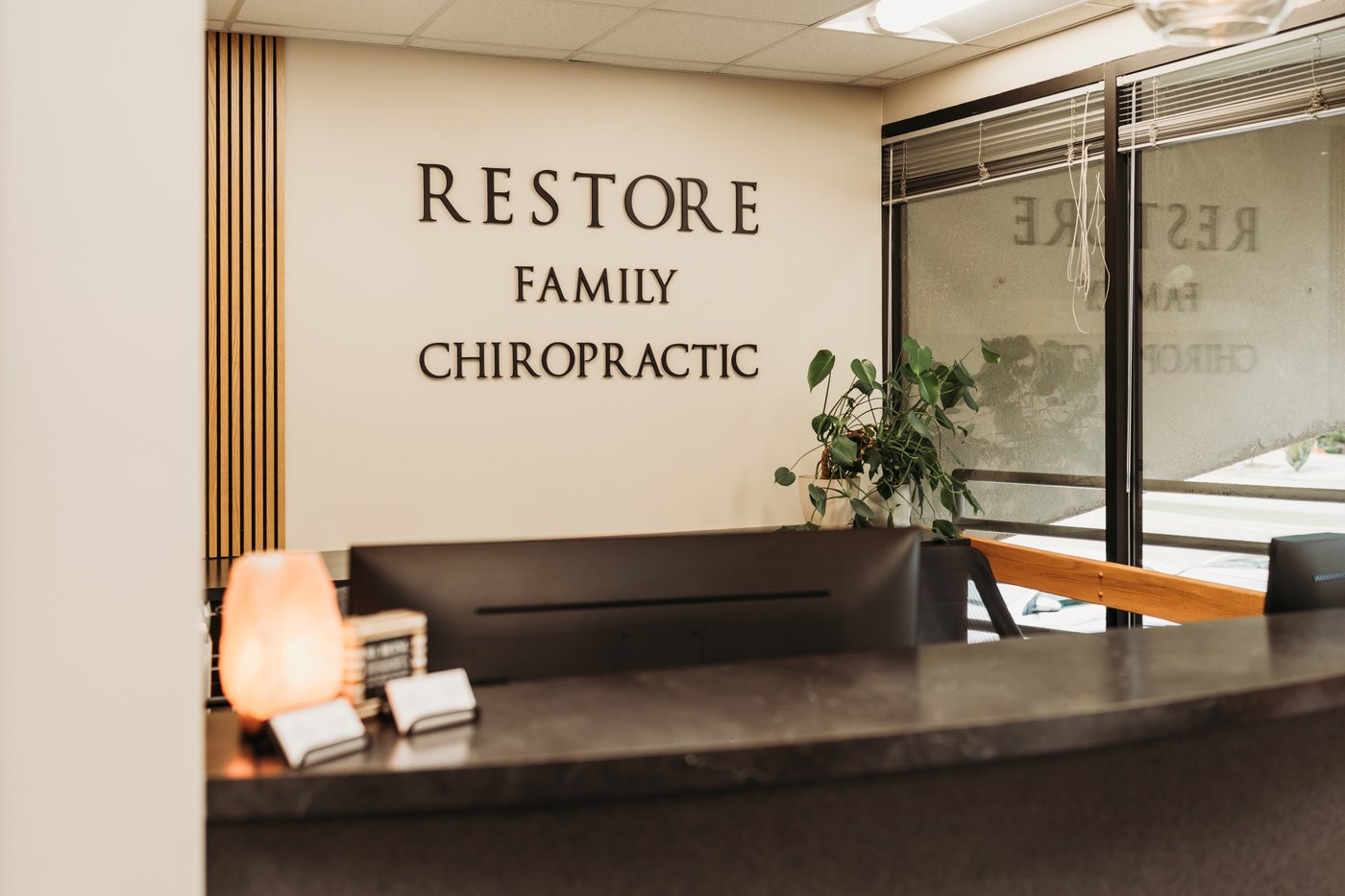 Restore Family Chiropractic welcoming modern reception area with wood paneling and salt lamp