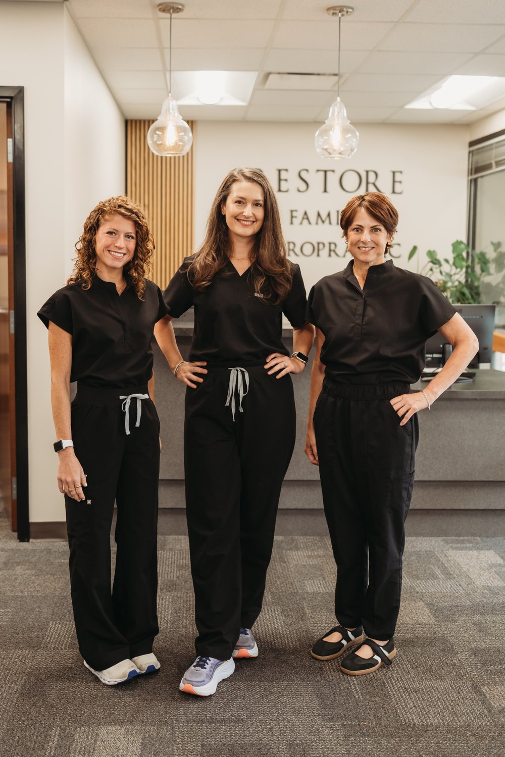Dr. Lauren Risalvato, Dr. Morgan Jones, and Stacy at the Restore Family Chiropractic front desk