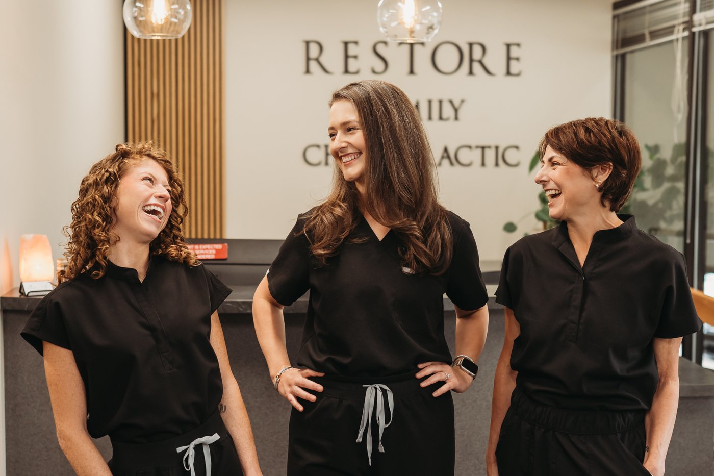 Restore Family Chiropractic team smiling together at the reception desk